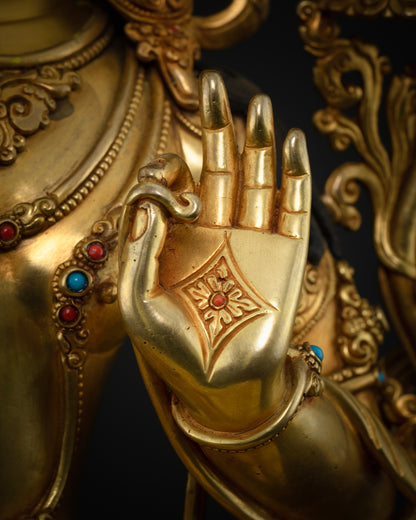Close-up of Manjushri statue’s Vitarka mudra hand with engraved diamond emblem and turquoise bracelet