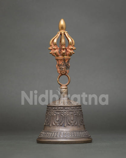 Close up of Tibetan Buddhist bell with copper handle, sacred deities, and intricate symbolic motifs