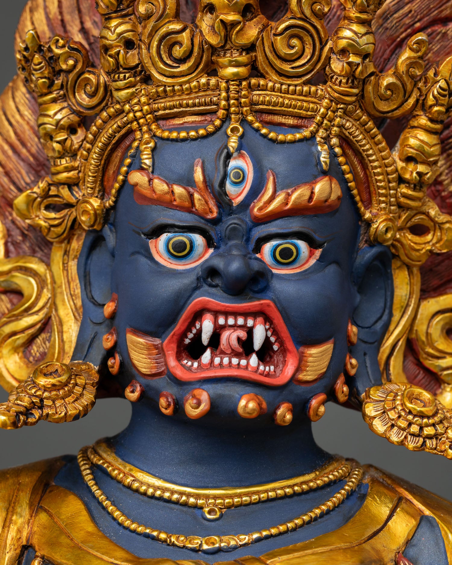 Close-up of Troma Nagmo Statue's fierce face with hand-painted details and gold crown.