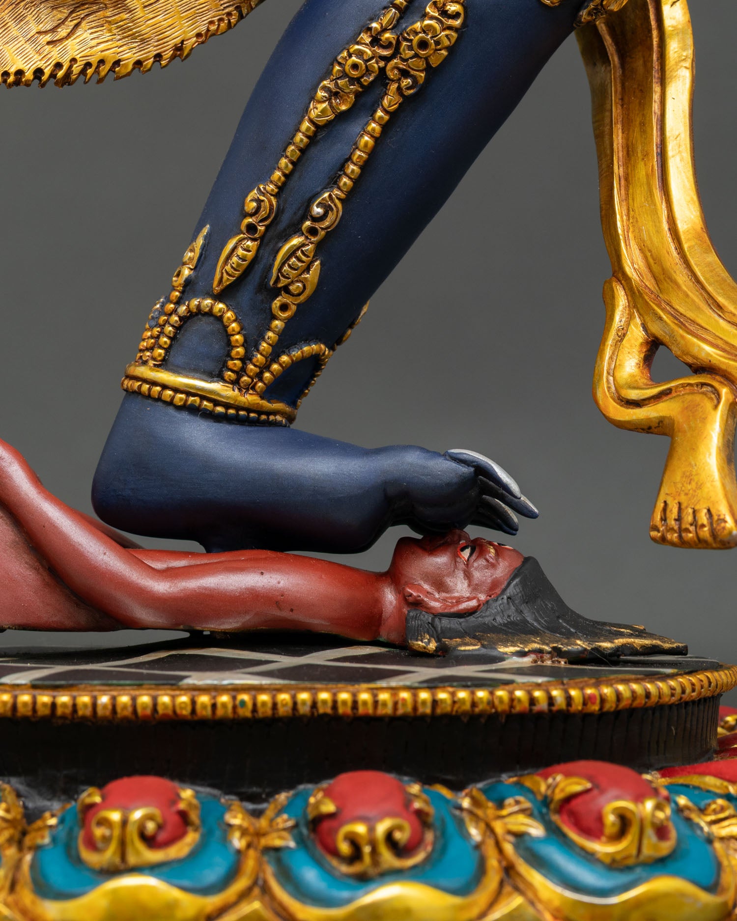Close-up of Troma Nagmo Statue's foot subduing ignorance on a decorative lotus base.