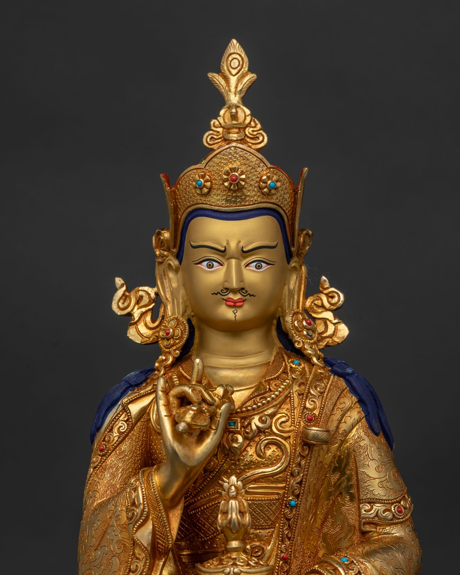 Close up of Tsokye Dorje Statue with gold painted face and semi precious stones