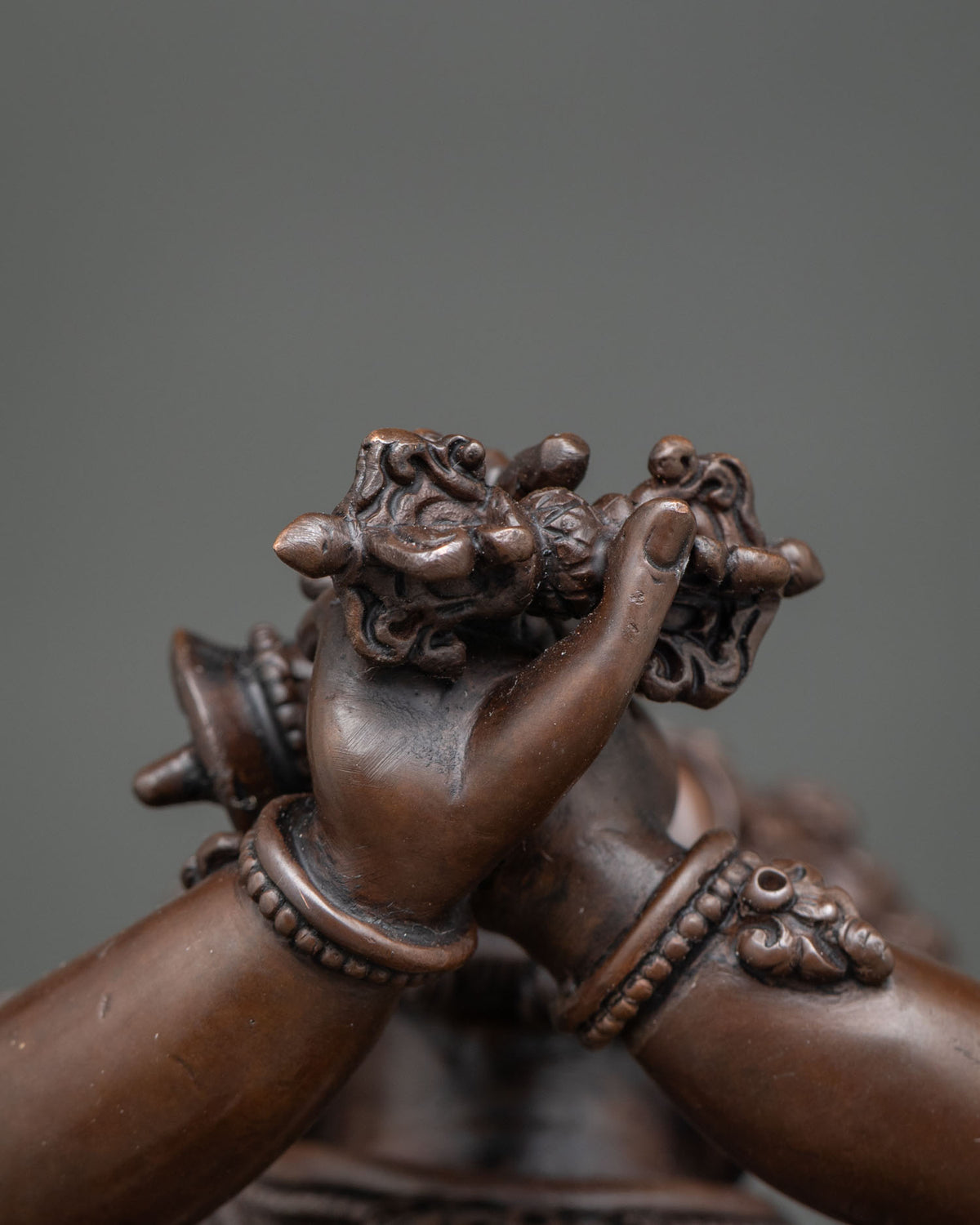 Close-up of Vajradaka’s hands holding a ritual vajra at the chest