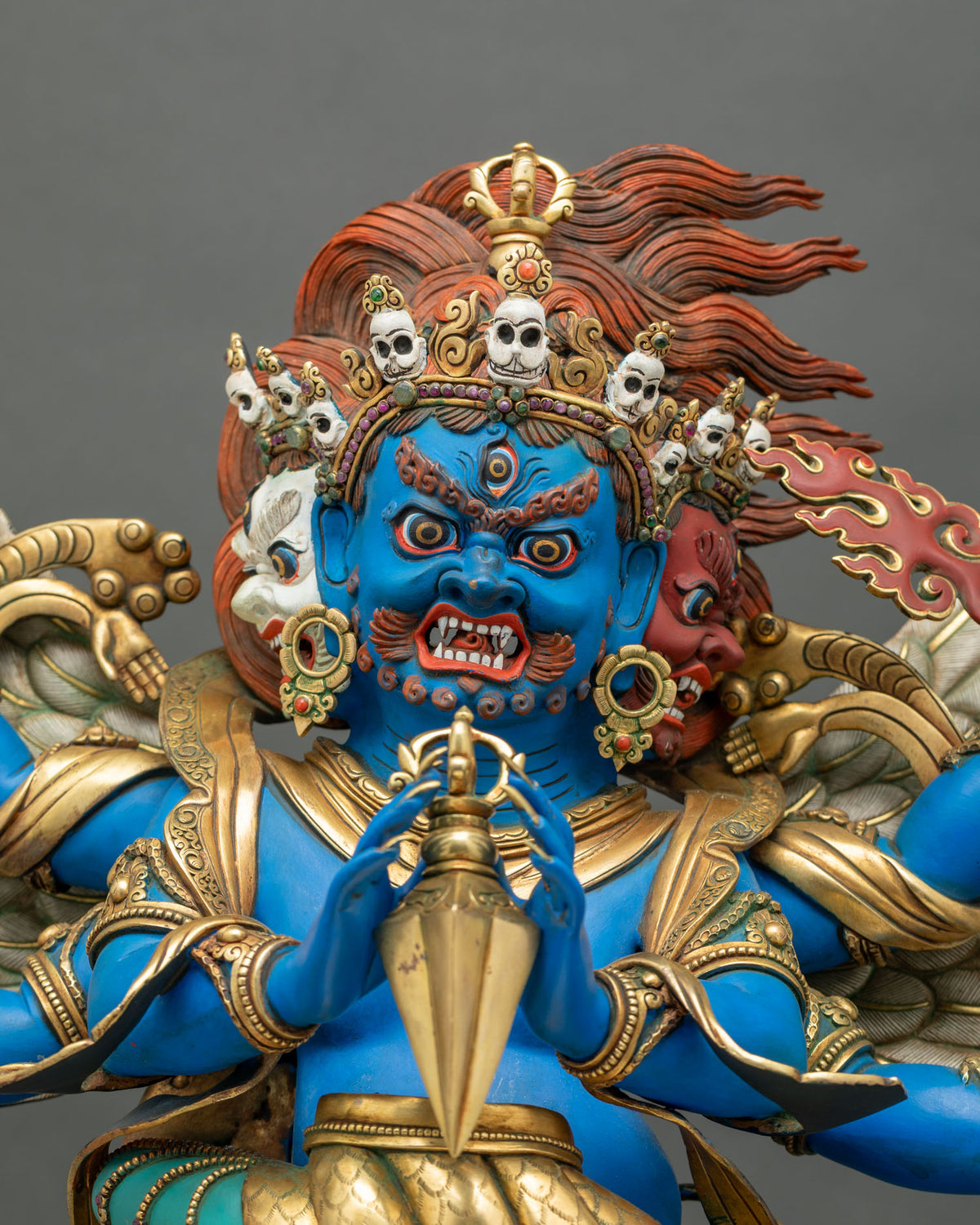 Close-up of Vajrakilaya blue face with skull crown, third eye and gilded phurba held in front