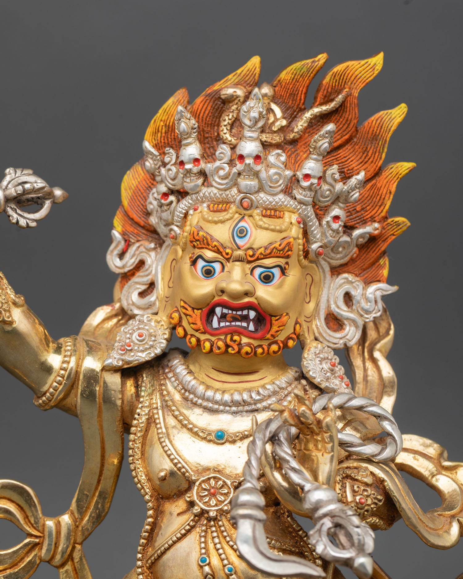 Close up of Vajrapani gold-painted face wide third eye bared fangs blazing hair intricate Newari artistry