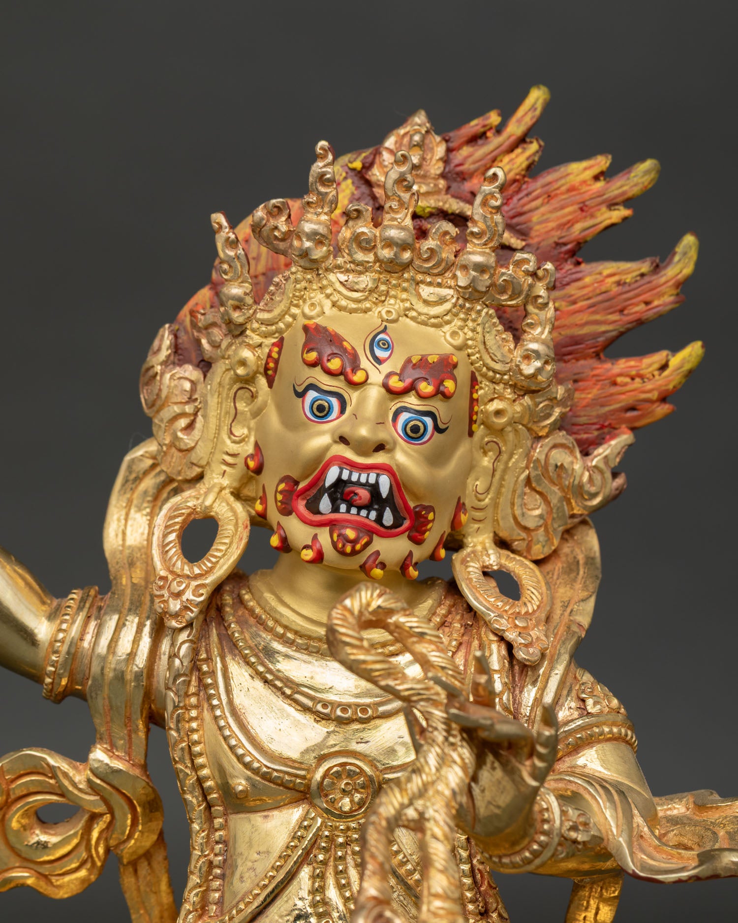 close-up of vajrapani statue showing wrathful expression and gold-painted face