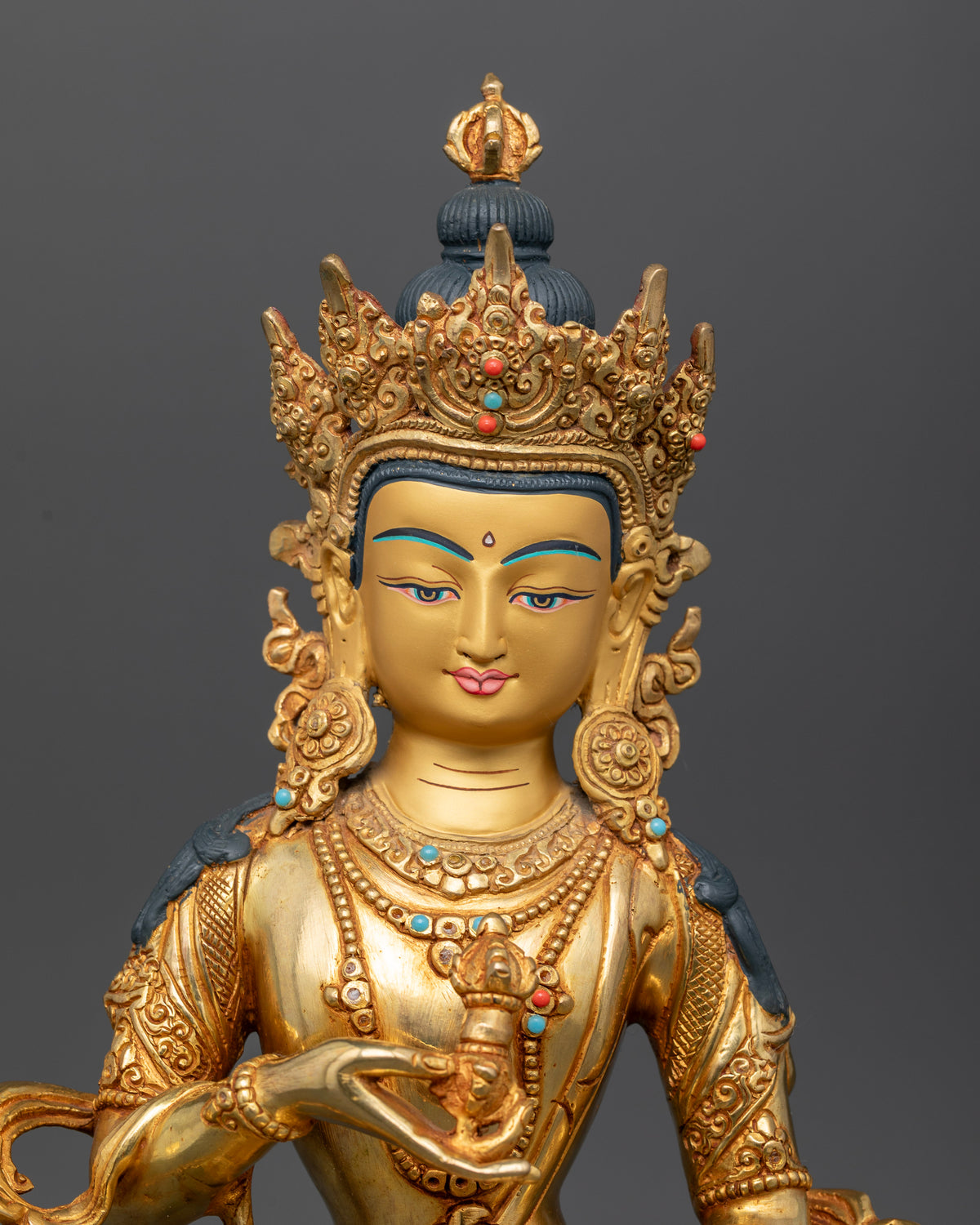 Close up of vajrasattva 24k gold painted face with semi precious stone embellishments.