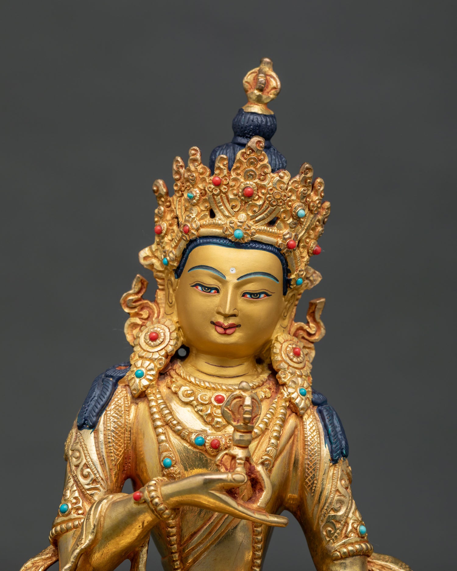 Close up of Vajrasattva statue showing 24k gold painted face ornate crown and intricate hand carved garment.