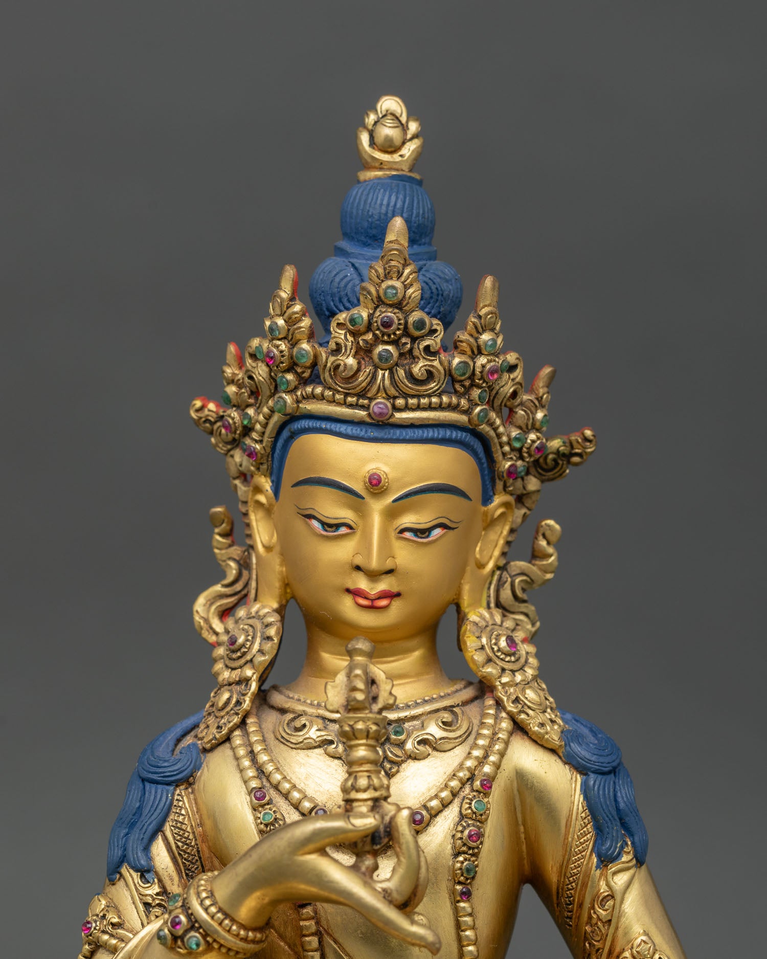 Close-up of Vajrasattva statue showing copper body, gemstones, and detailed gilding