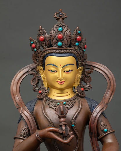 Close up of Vajrasattva statue with gold painted face and five pronged vajra.