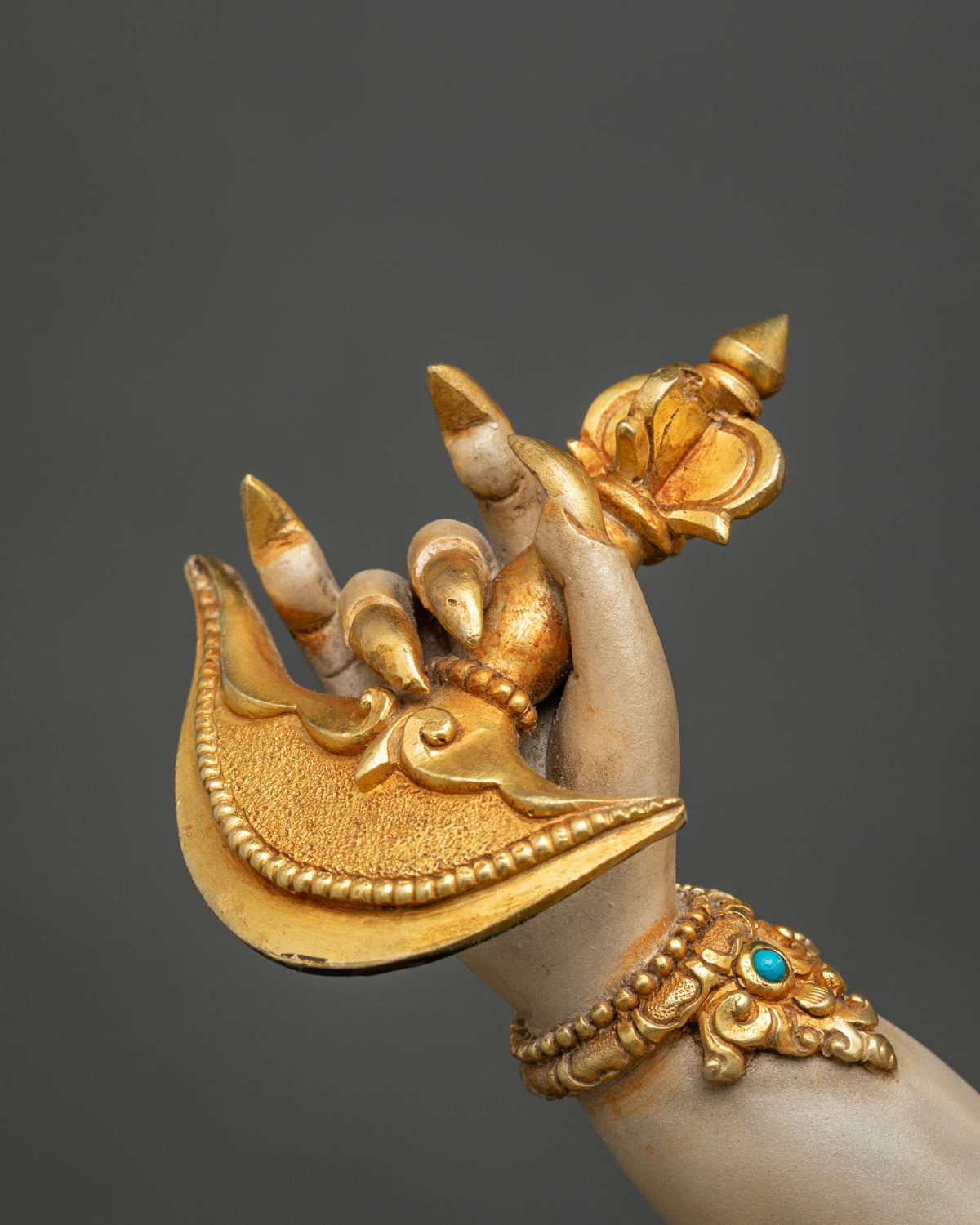 Close-up of White Mahakala hand holding a gold gilded kartika knife, set with turquoise