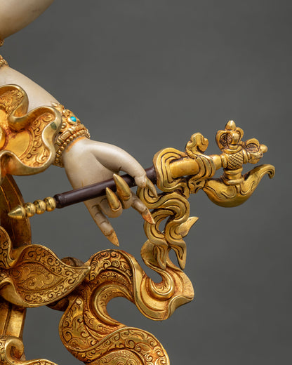 Close-up of White Mahakala hand holding a hook, with gold garments engraved with intricate scrollwork