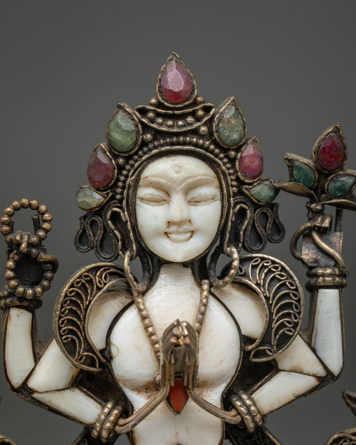 Close-up of white stone Chenrezig face, crown and Anjali Mudra hands on Avalokiteshvara statue