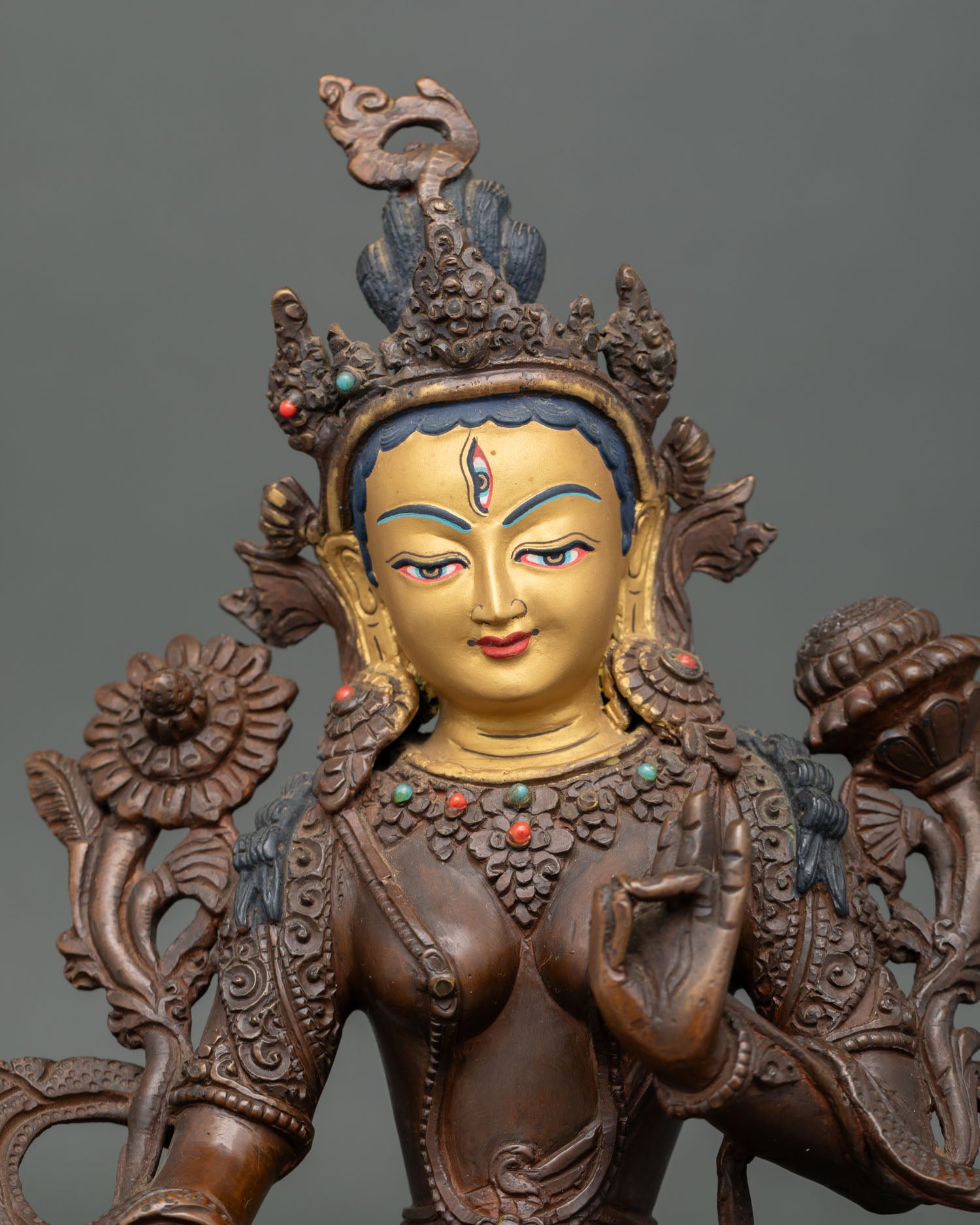 Close up of White Tara 24K gold painted face with oxidized copper craftsmanship.