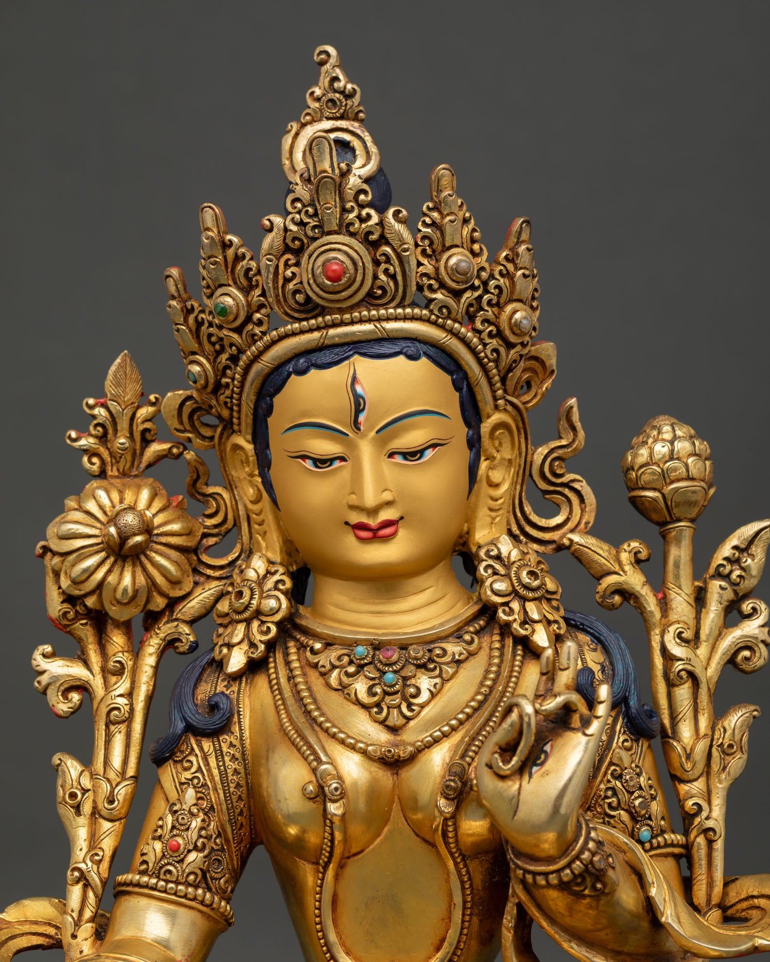 Close up of White Tara Buddhist statue showing gold painted face and seven all seeing eyes