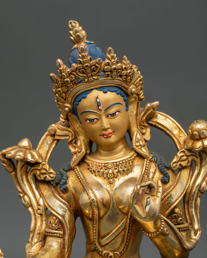 Close up of White Tara statue displaying serene gold painted face and compassionate expression