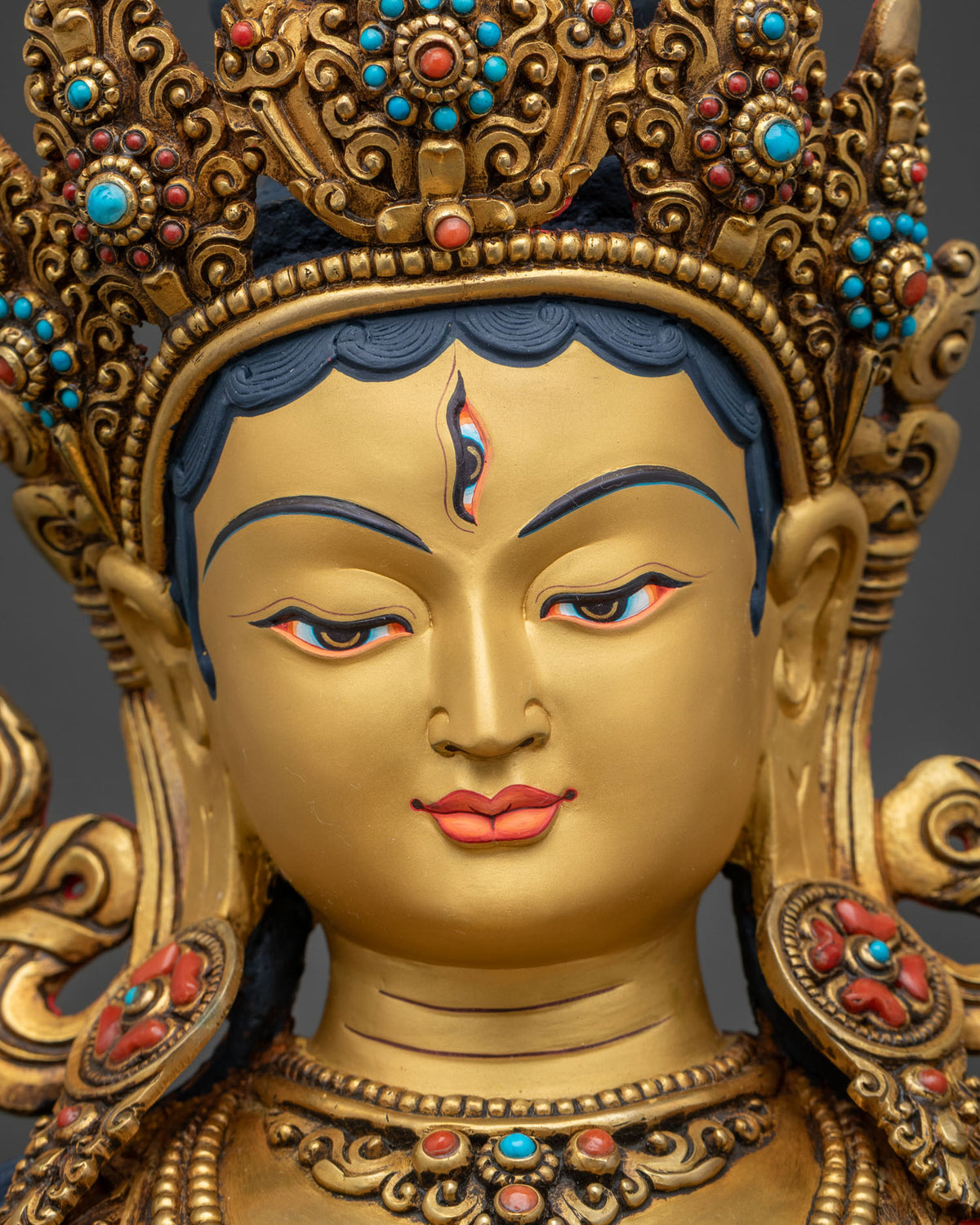 Close-up of White Tara statue's gold-painted face with seven compassionate eyes