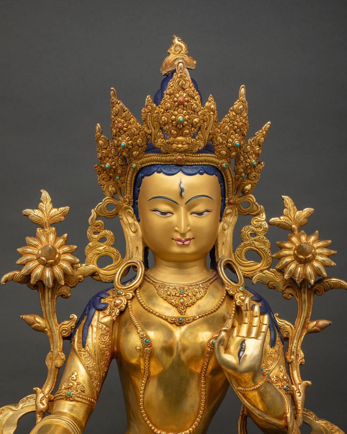 Close-up of White Tara statue, gold-gilded copper sculpture with lotus flowers