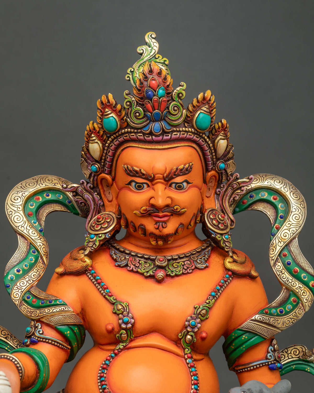 Close-up of Yellow Dzambhala statue featuring a semi-wrathful expression, intricate gold ornaments, and multicolored celestial garments.