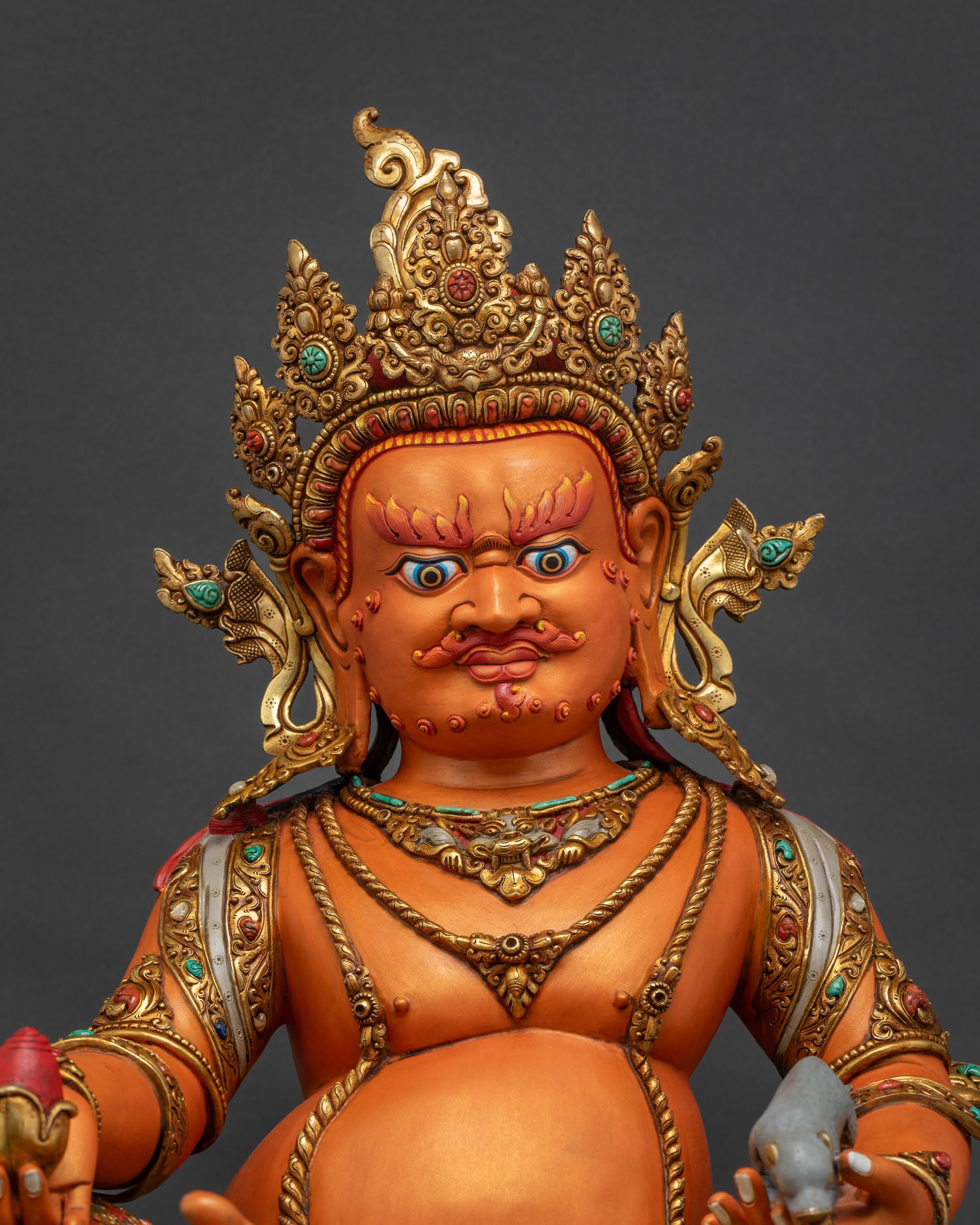 Close up of Yellow Dzambhala statue showing gold gilded jewelry and semi precious stone details