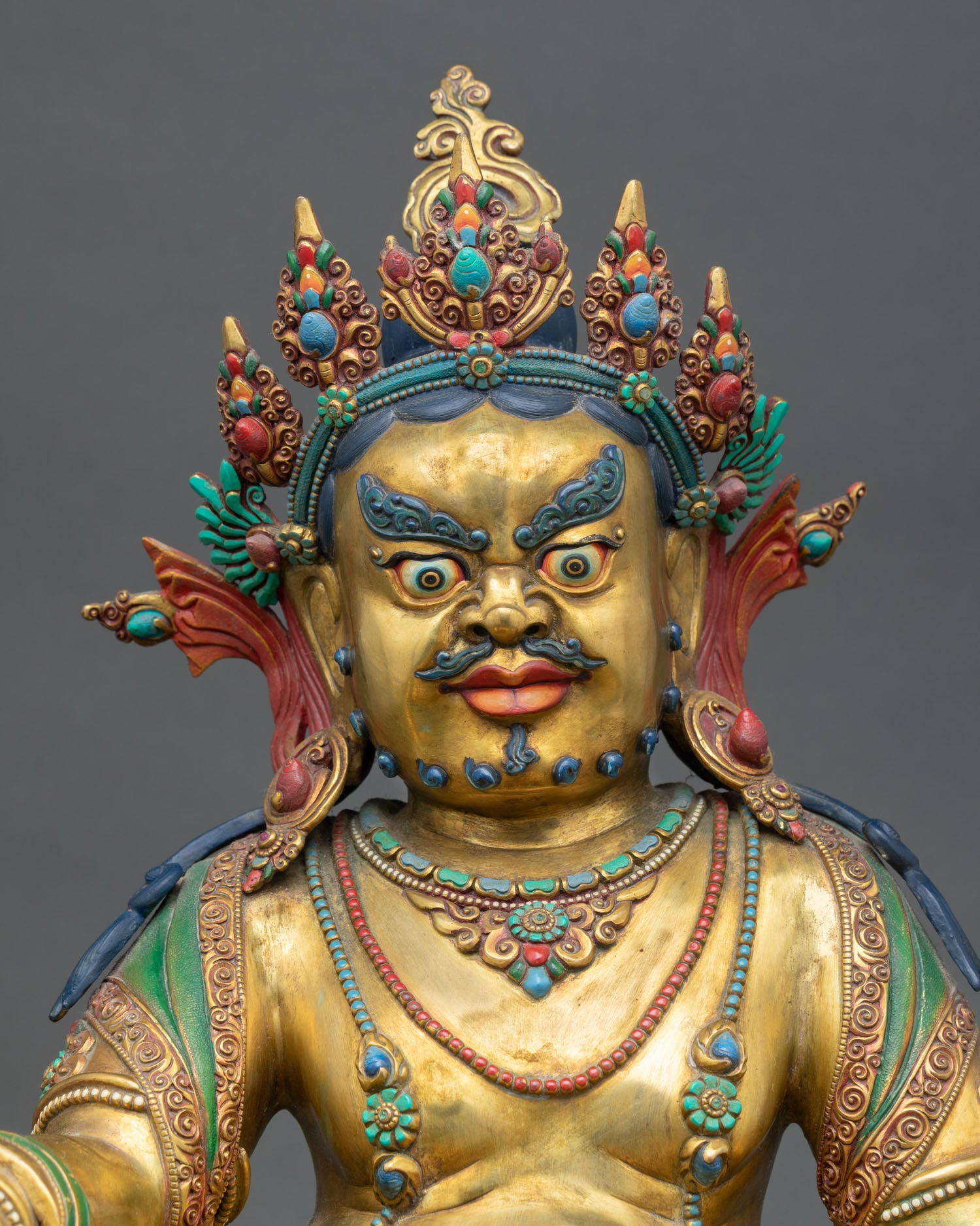 Close up of Yellow Dzambhala statue with hand painted details and semi precious stones