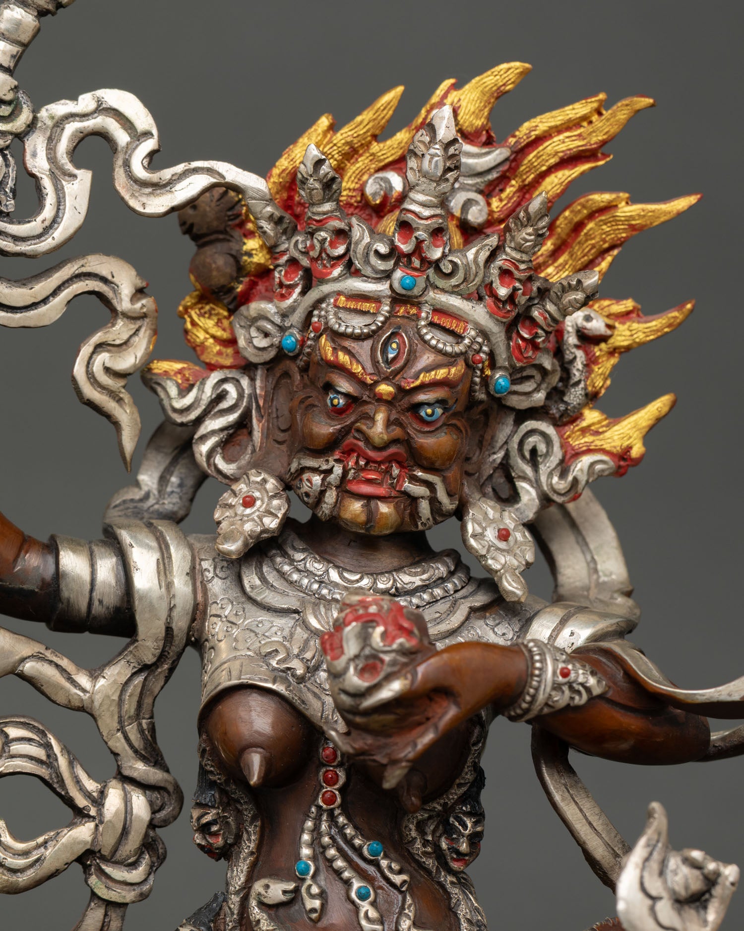 Close up Palden Lhamo wrathful face adorned with semi precious stones and sacred ornaments