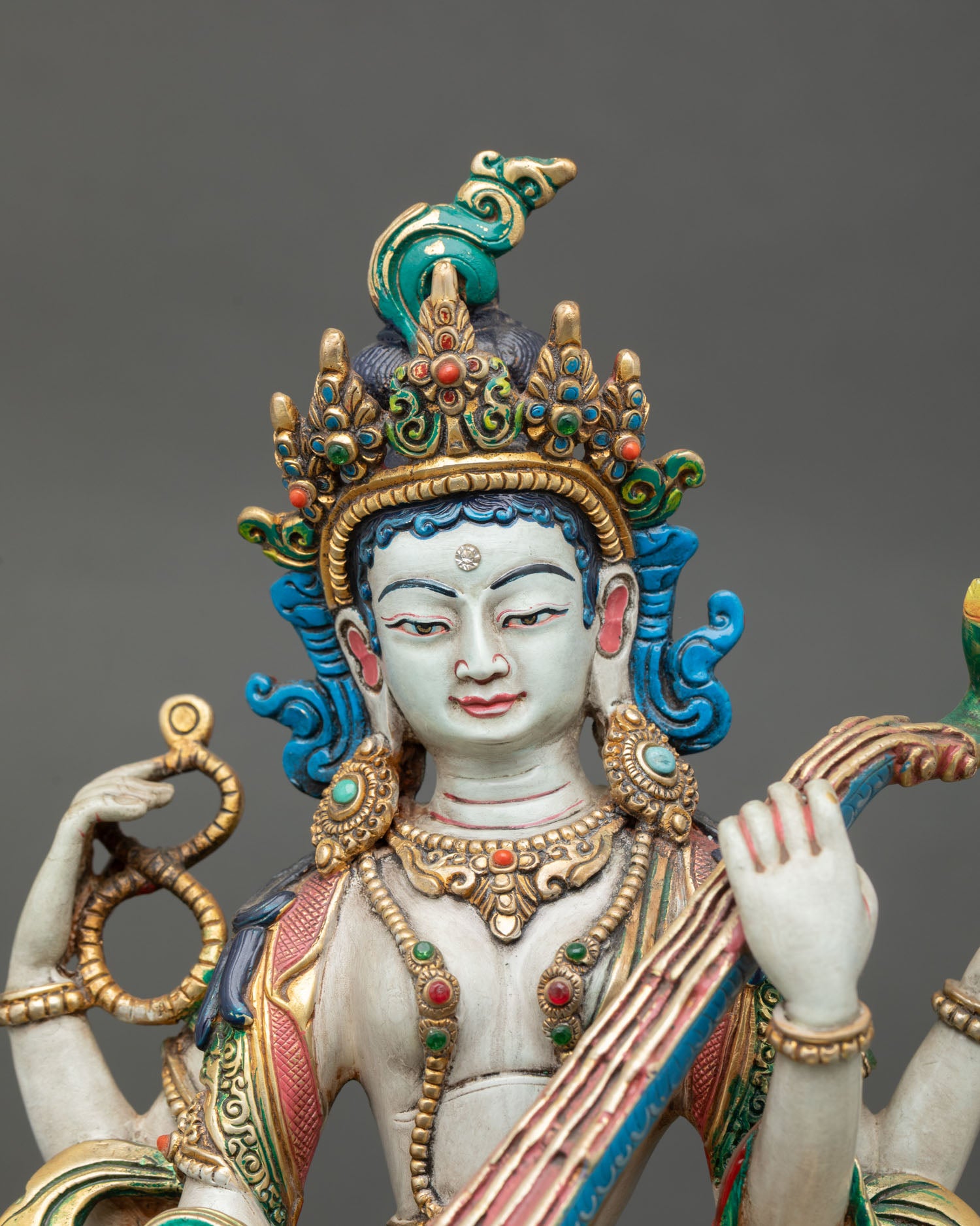Close up Saraswati face with gold-painted expression detail, and semi-precious stones