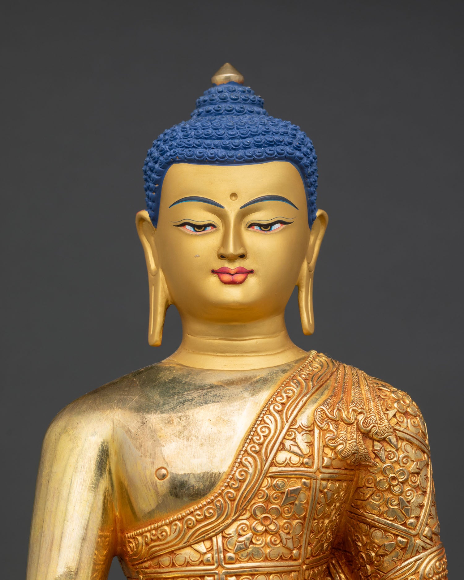 Close up Shakyamuni Buddha face detail gold painted finish, Vajrayana Buddhist sculpture Himalayan craftsmanship spiritual decor