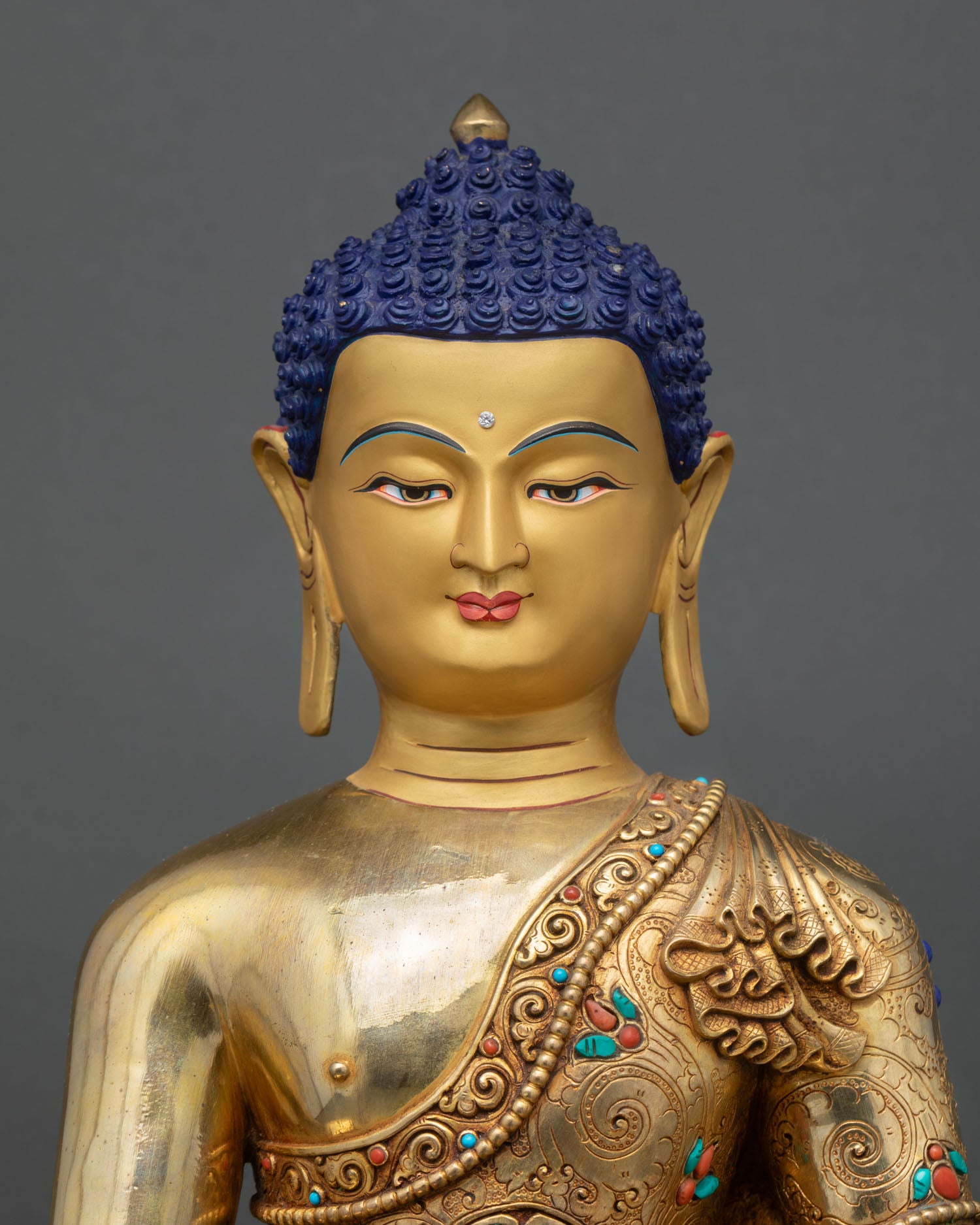Close up Shakyamuni Buddha face detail gold toned finish semi precious stone accents monastic robe Himalayan Buddhist sculpture