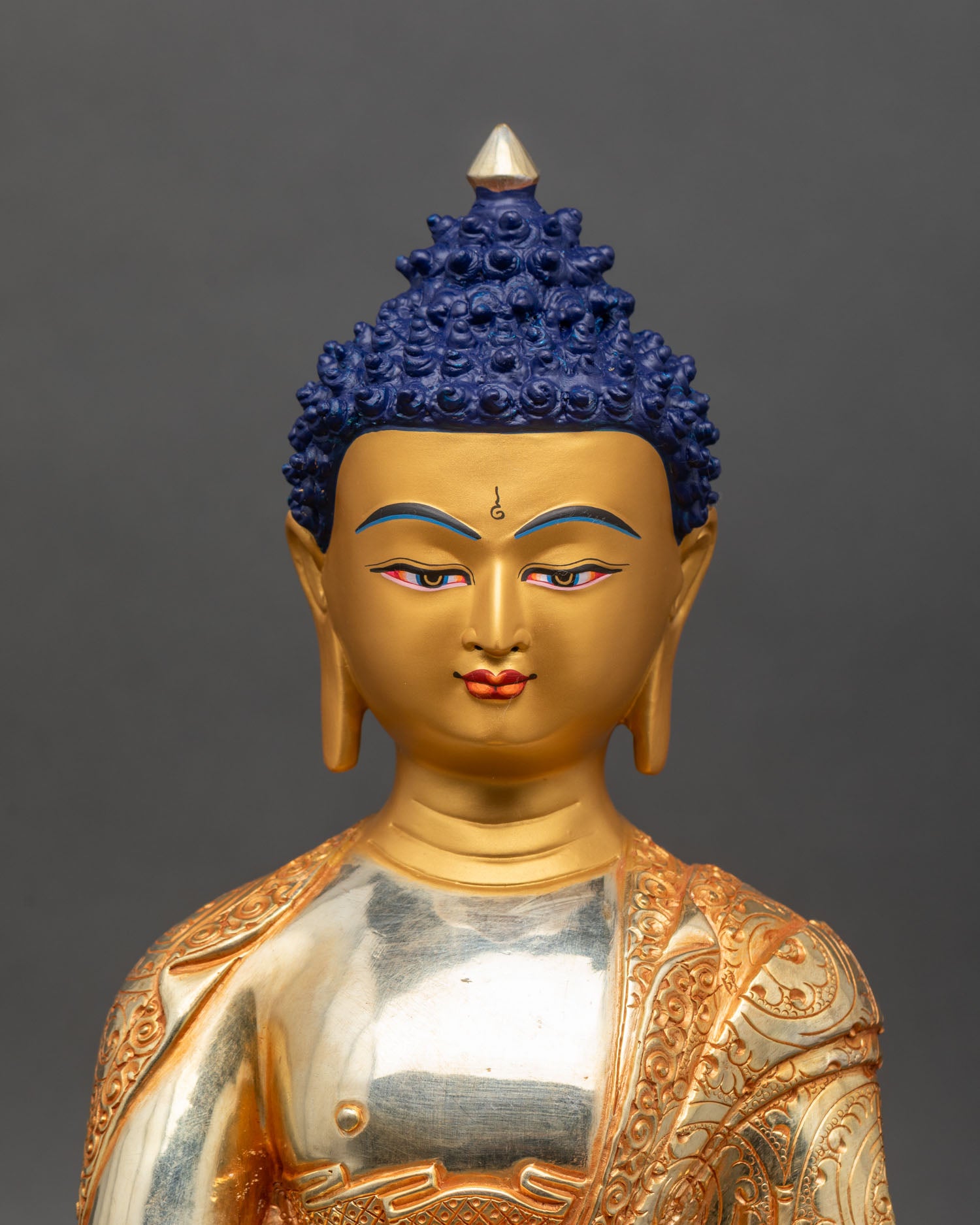 Close-up of Shakyamuni Buddha's face, a gold-painted copper Himalayan sculpture