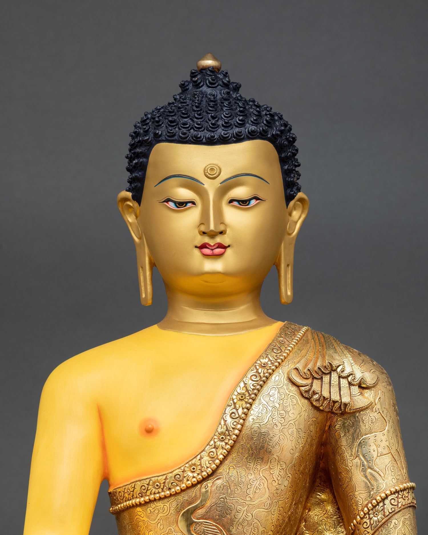 Close up Shakyamuni Buddha gold painted face copper statue acrylic detailing spiritual decor