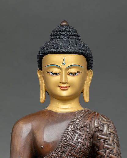 Close up Shakyamuni Buddha serene gold face flowing monastic robes detail Himalayan Buddhist sacred statue