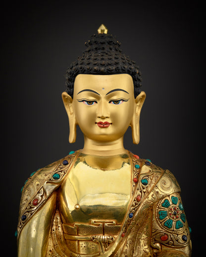 Close-up of Shakyamuni Buddha statue showing gold face and repoussé robe detail