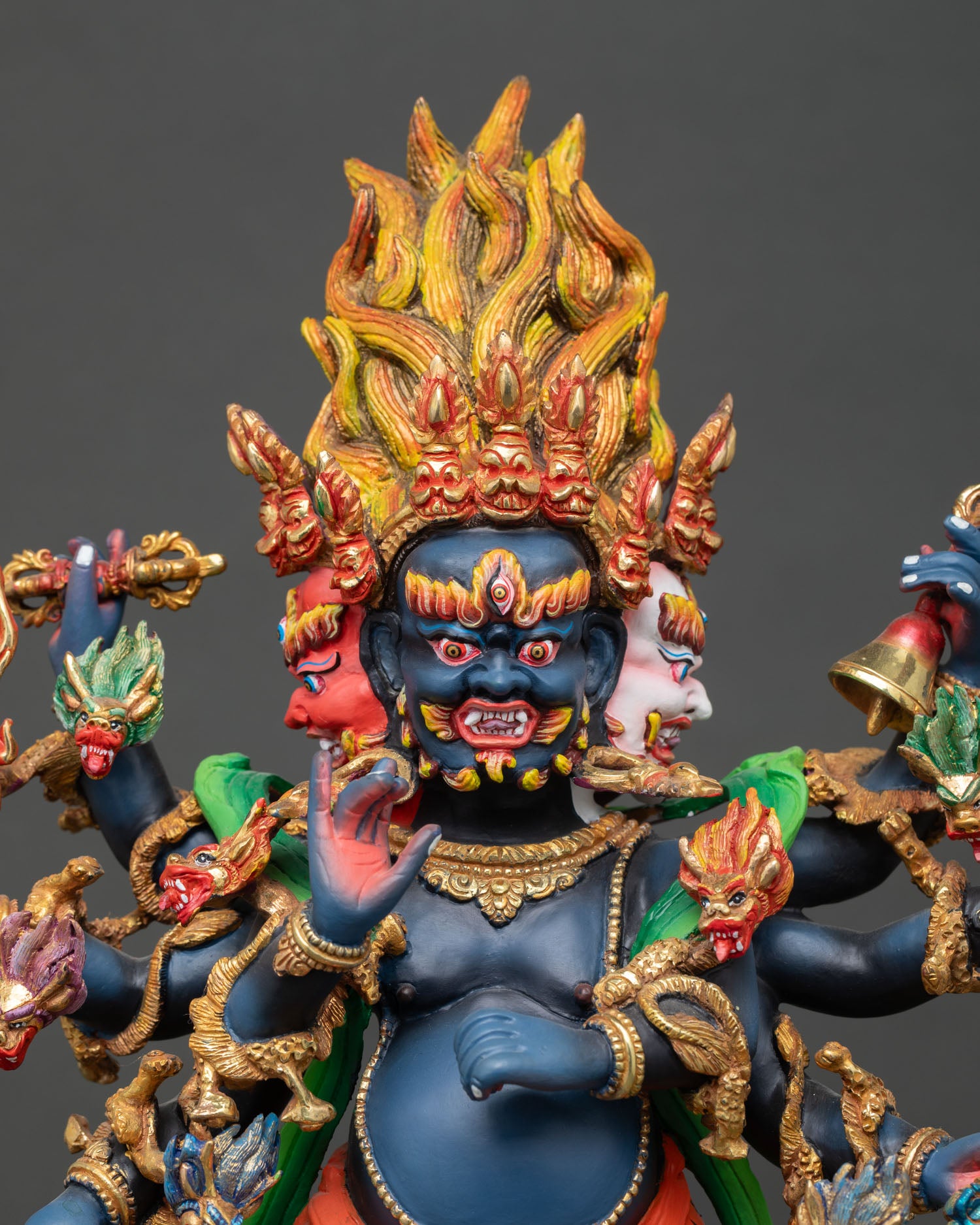 Close up Ucchusma three wrathful faces with multiple arms holding ritual implements symbolizing destruction of ignorance and obstacles