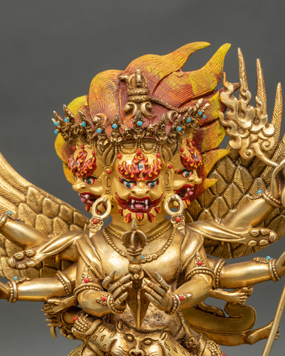 Close up of Vajrakilaya statue showing three gold-painted faces and ritual attributes.