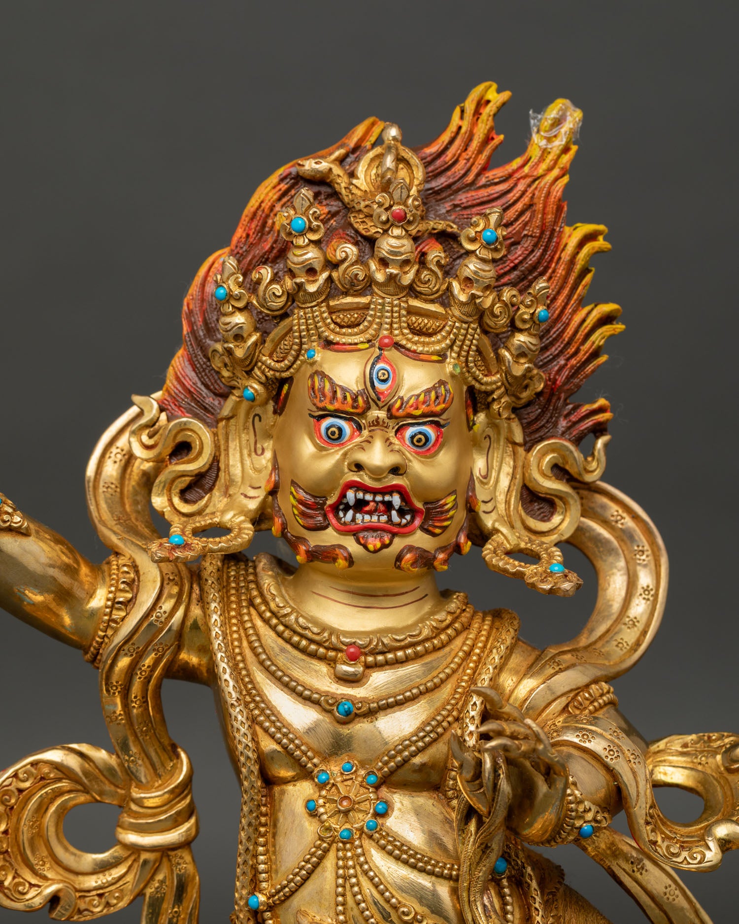 Close up Vajrapani statue with gold painted face wrathful expression vajra and detailed stone adorned ornaments