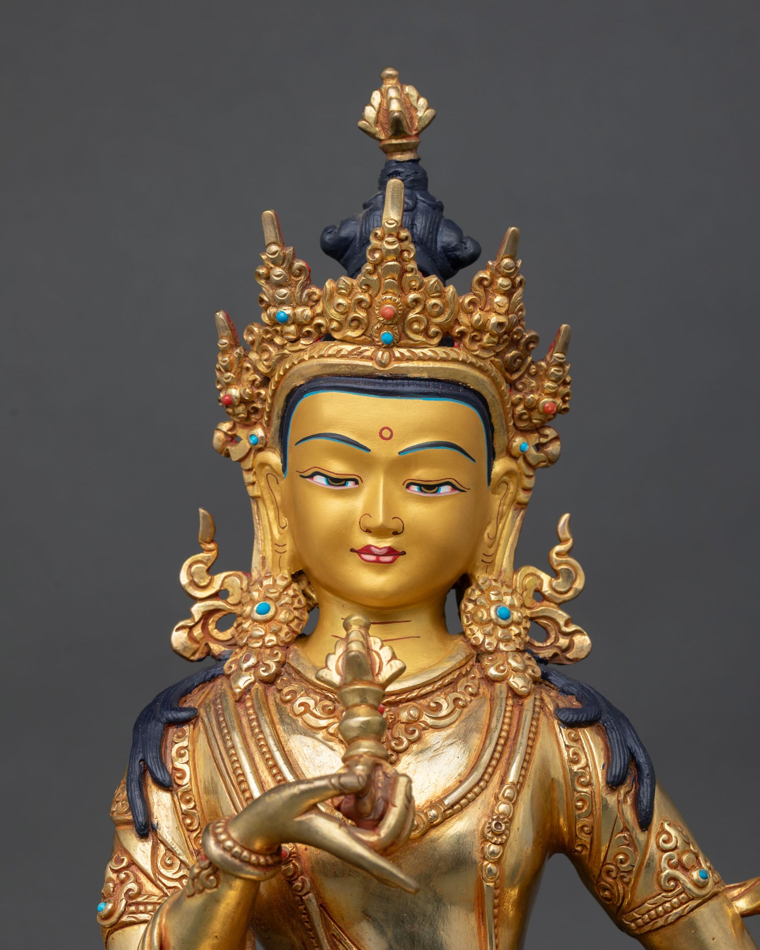 Close up Vajrasattva gold painted serene face detail jeweled crown turquoise coral inlay copper statue Himalayan Buddhist craftsmanship