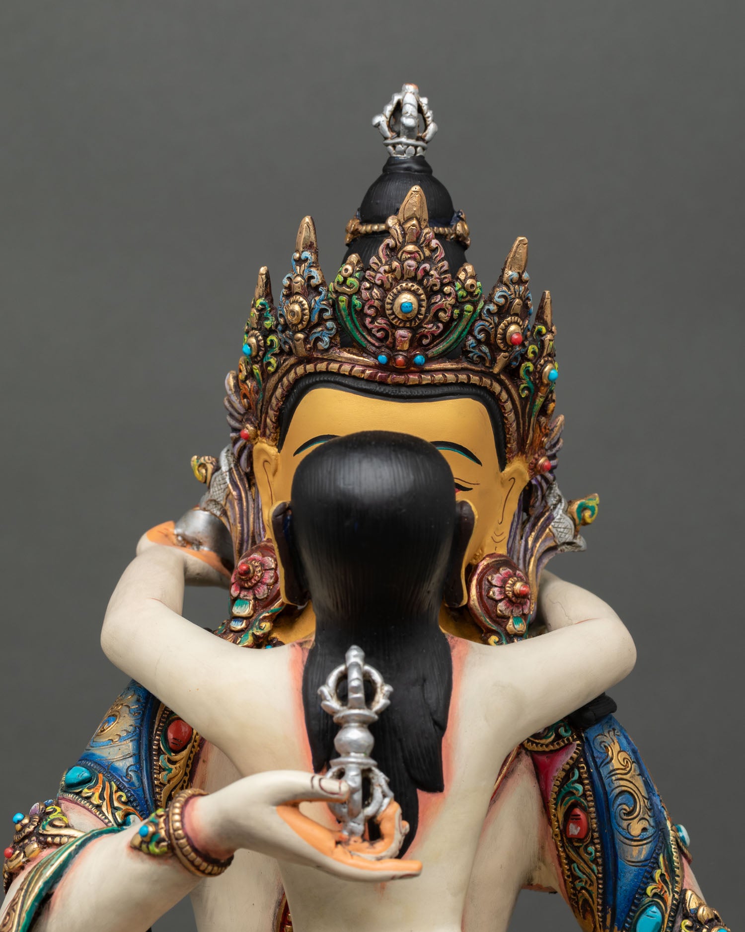 Close up Vajrasattva statue gold painted face vajra and bell silver plated accents serene expression Himalayan craftsmanship detail