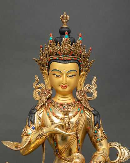 Close up of Vajrasattva statue showing gold painted face, holding Vajra and Ghanta, symbolizing spiritual blessings.
