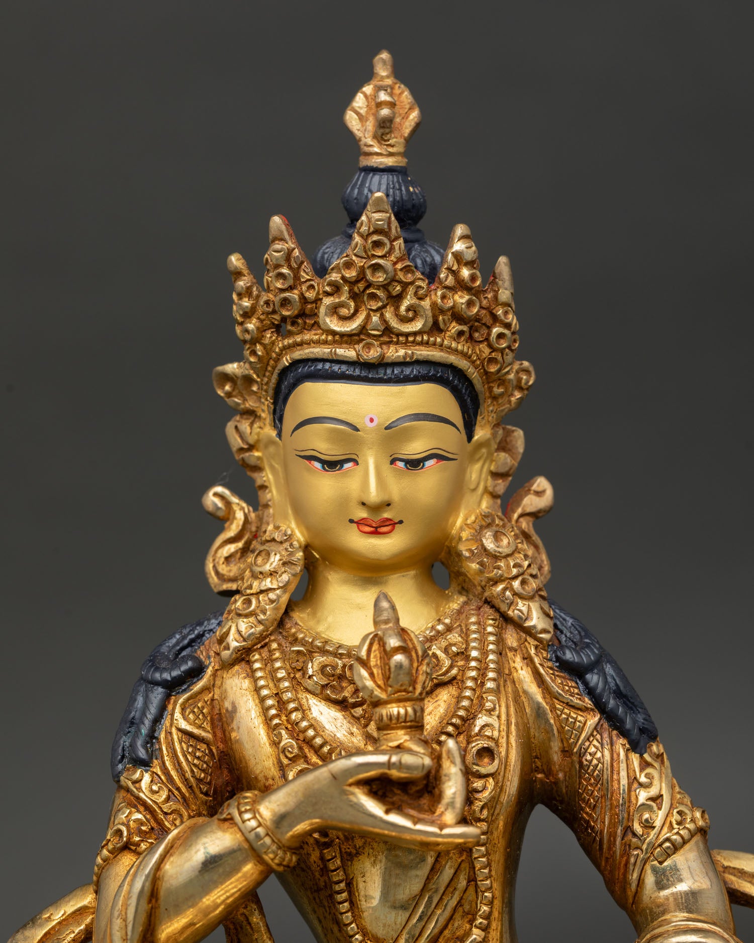 Close up Vajrasattva statue, detailed gold painted face, holding vajra