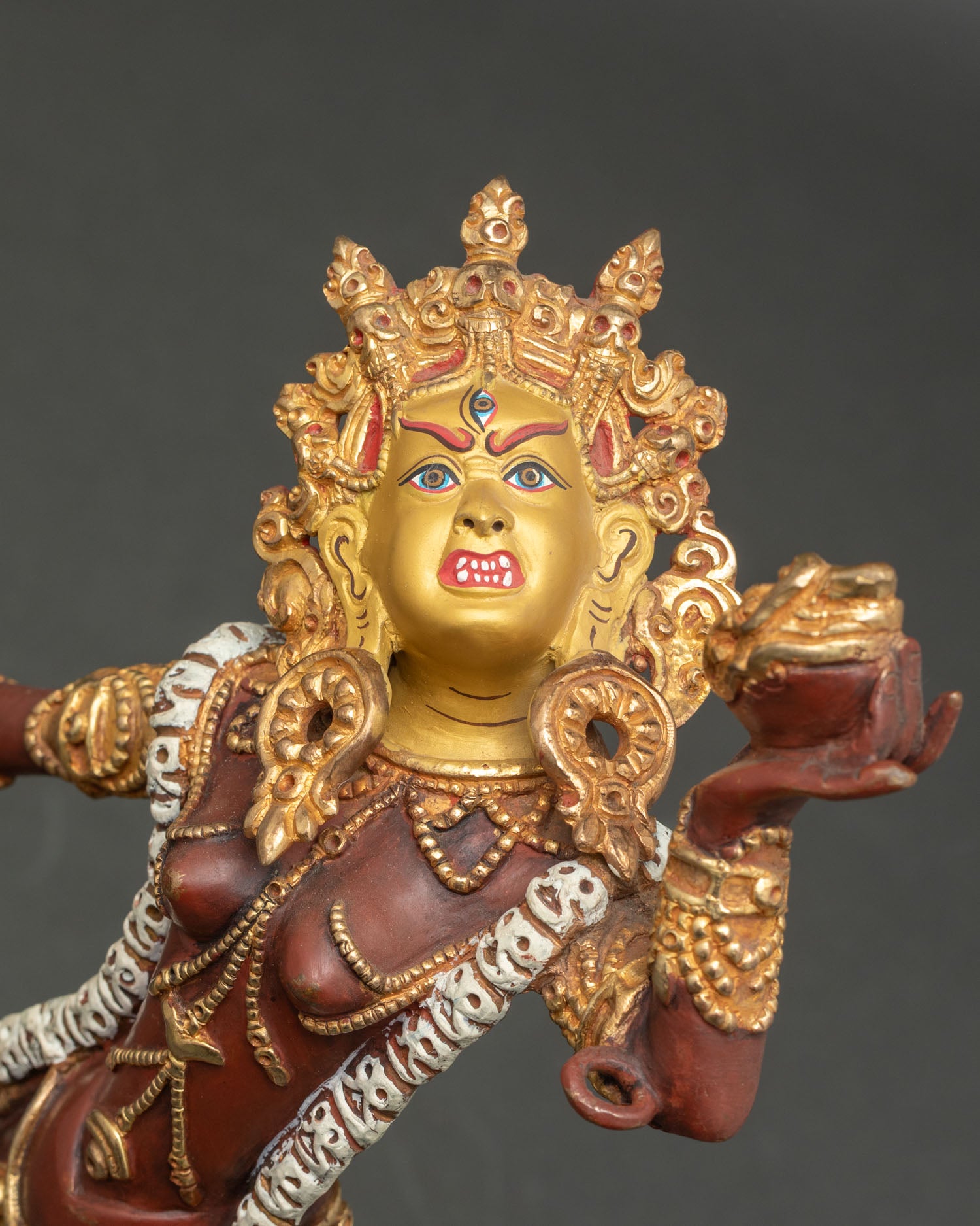 Close-up Vajrayogini gold-painted face details with halo and trident