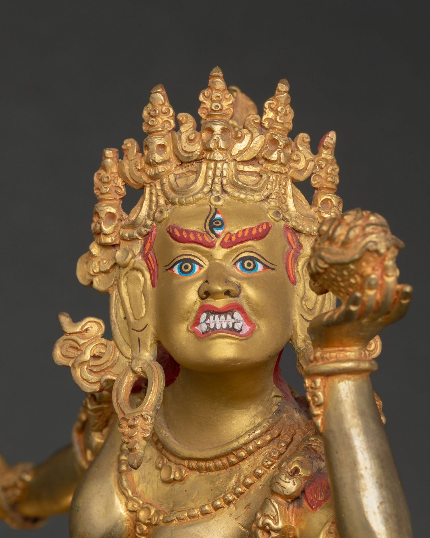 Close up Vajrayogini goddess statue showing gold painted face third eye wrathful expression, skull cup with intricate Nepalese craftsmanship.