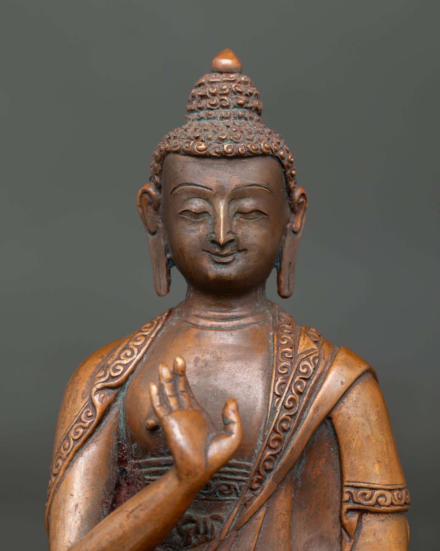 Close up view of Amoghasiddhi Buddha face and hand carved monk robe details.