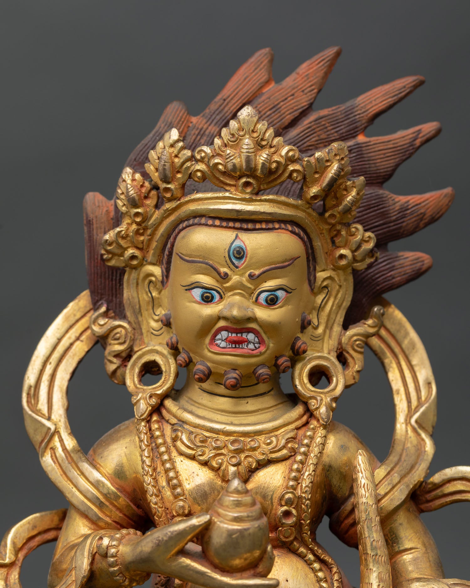 Close up view of Black Dzambhala face showing gold painted details and intricate Himalayan Buddhist craftsmanship