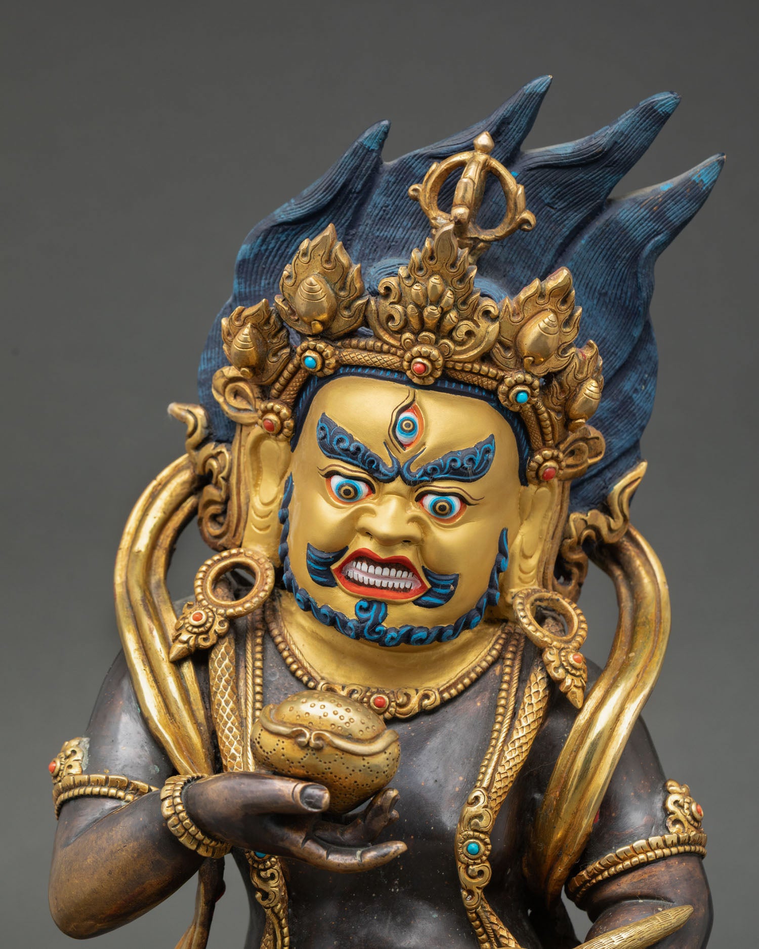 Close up view of Black Dzambhala statue face detail,  turquoise coral inlay