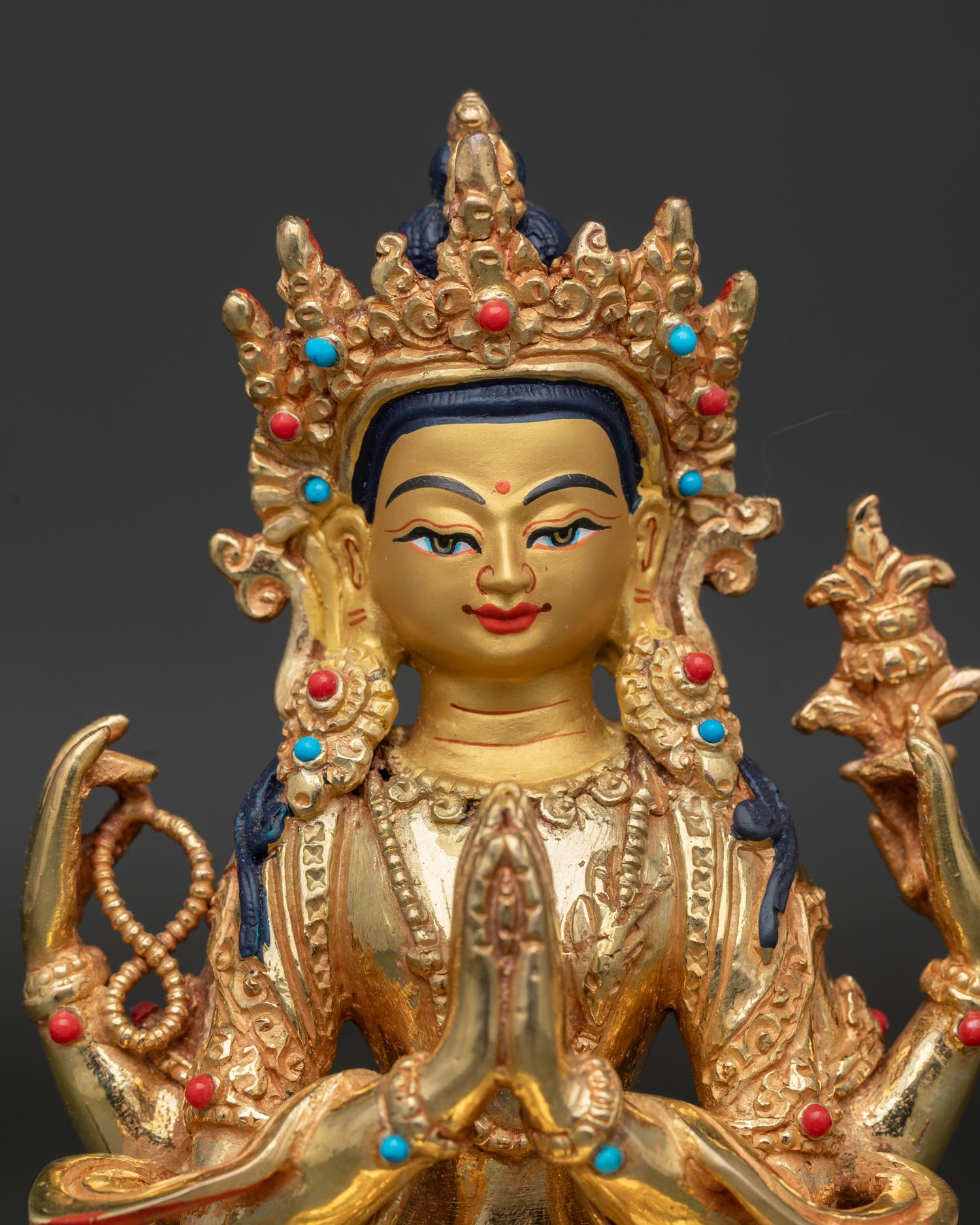 Close up view of Chenrezig gold painted face with wish fulfilling jewel and lotus pedestal