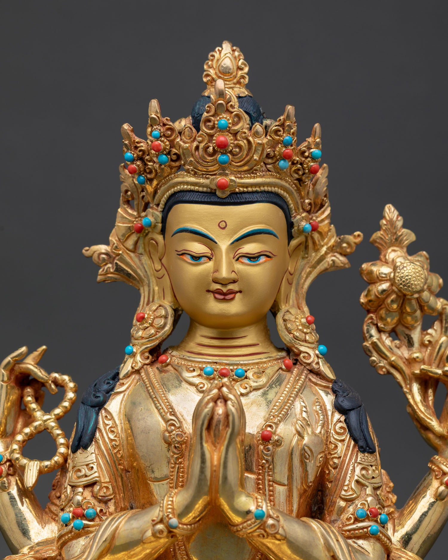 Close up view of Chenrezig statue with serene gold painted face symbolizing compassion and enlightened awareness