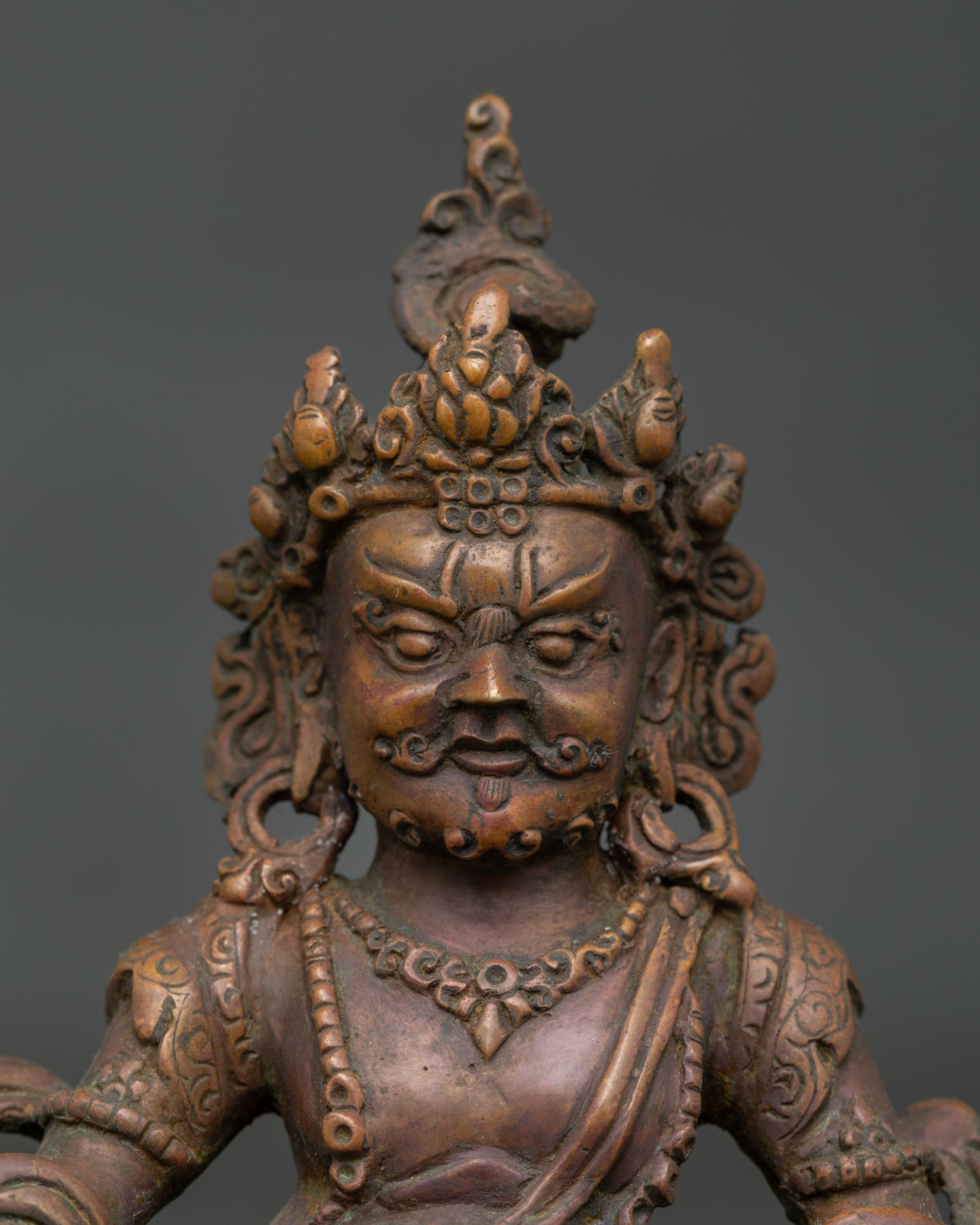 Close up view of Dzambhala statue face ornaments and intricate handcrafted details by Nepalese artisans.