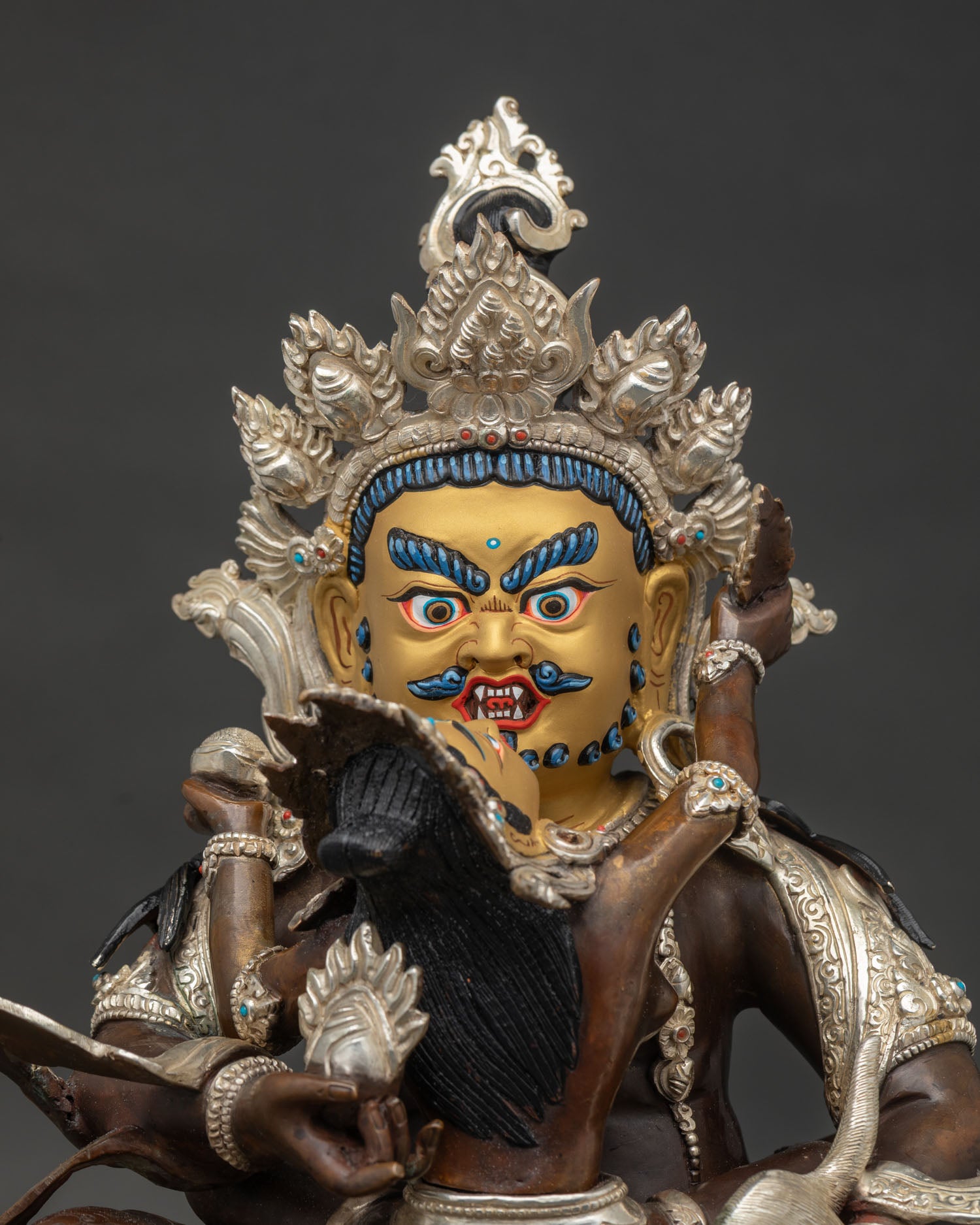 Close up view of Dzambhala with gold painted face and silver plated copper finish