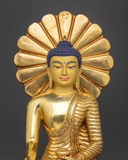 Close-up view of gold-gilded Shakyamuni Buddha statue showing detailed monastic robes, floral patterns, and turquoise halo accents