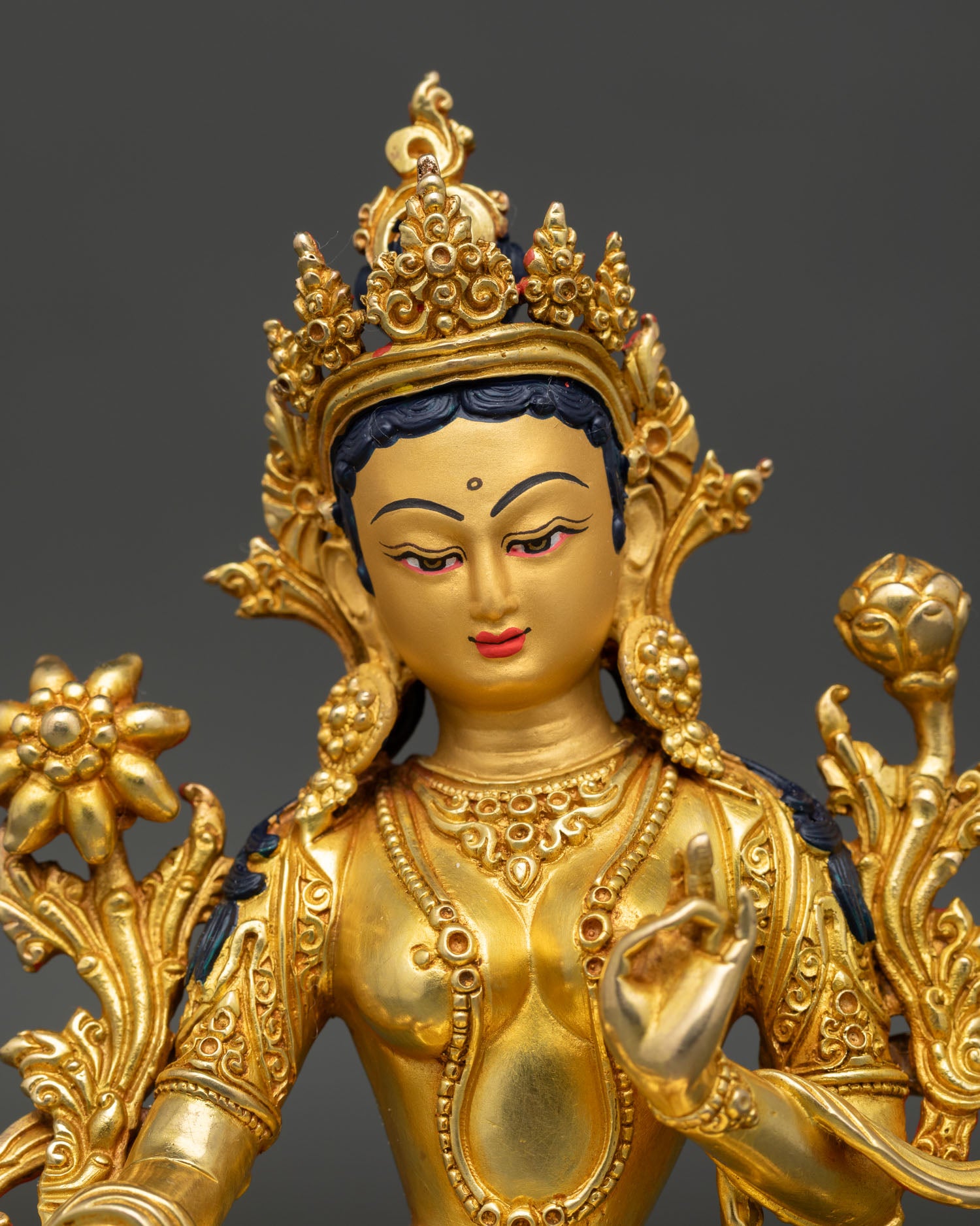 Close up view of Green Tara Buddhist goddess statue, showing compassionate expression and intricate Himalayan details